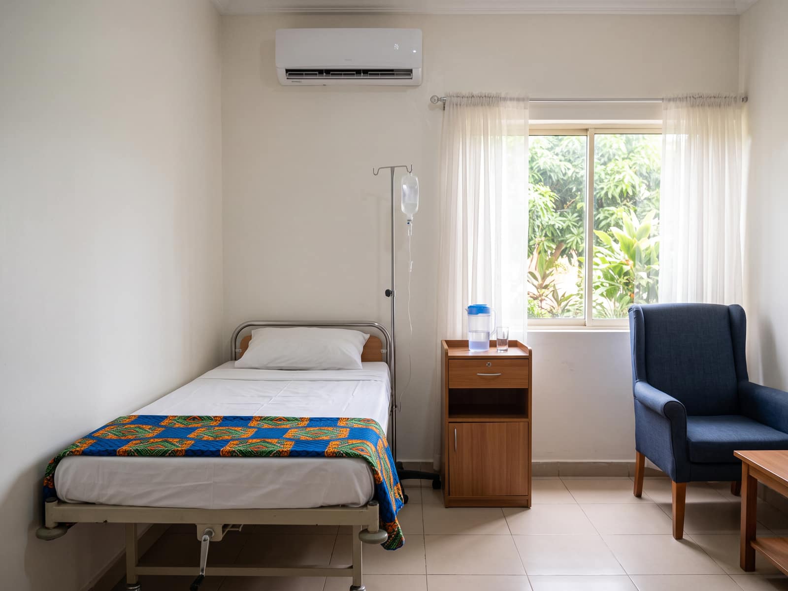 A private room with a hospital bed, a drip stand, a chair for a relative and a window